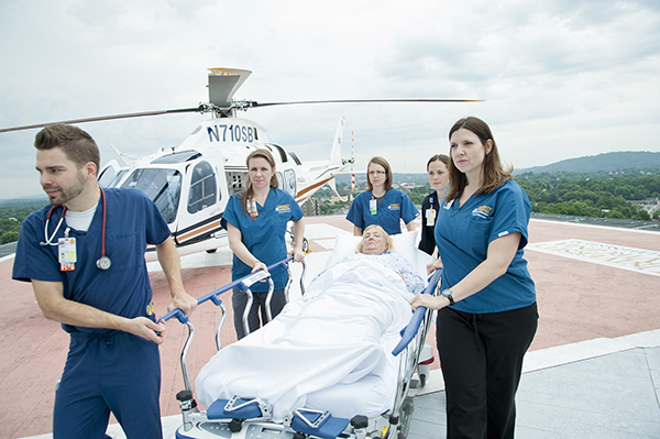 Five hospital employees wheeling a patient in a gurney from the Pegasus helicopter
