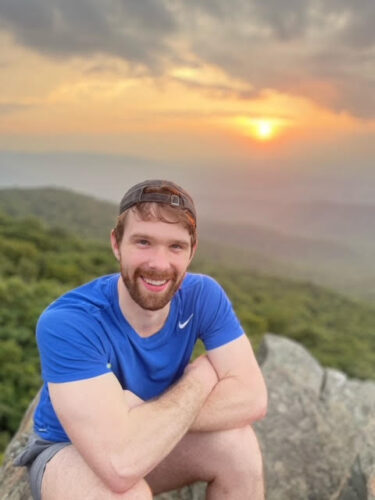 University of Virginia Thomas Quisenberry, MD, Surgery Resident smiles at sunset in the Blue Ridge Mountains.